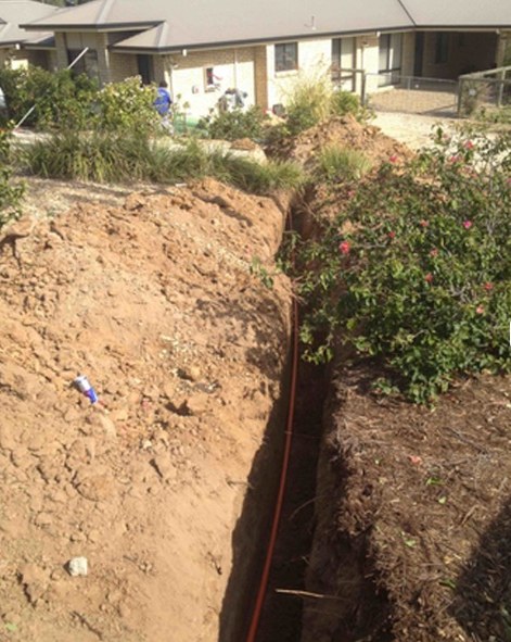 Trench dug through a garden for underground electrical conduit to a house