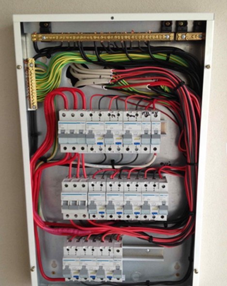 Fully wired residential switchboard with rows of circuit breakers and colour-coded cabling